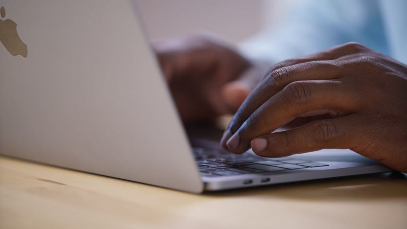 Close-up of hands typing on a laptop, delivering a project
